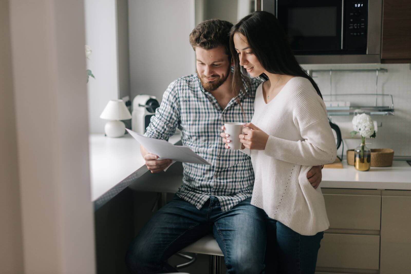 young smiling couple in kitchen looking at papers