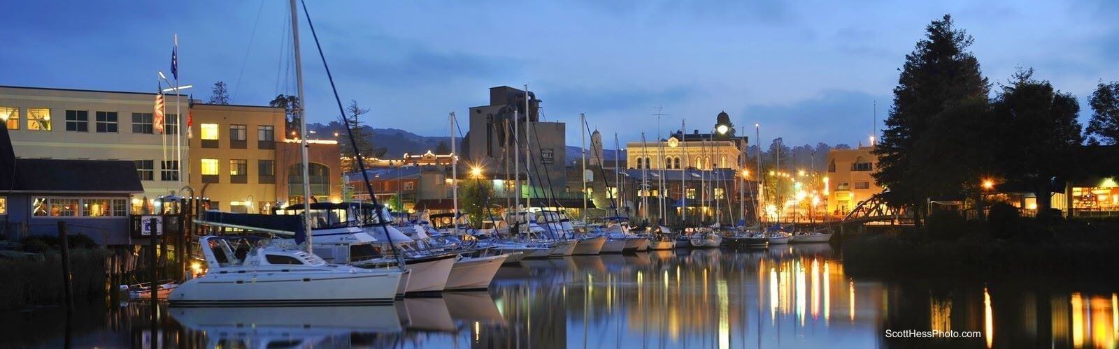 Night view of Petaluma from river with sailboats.