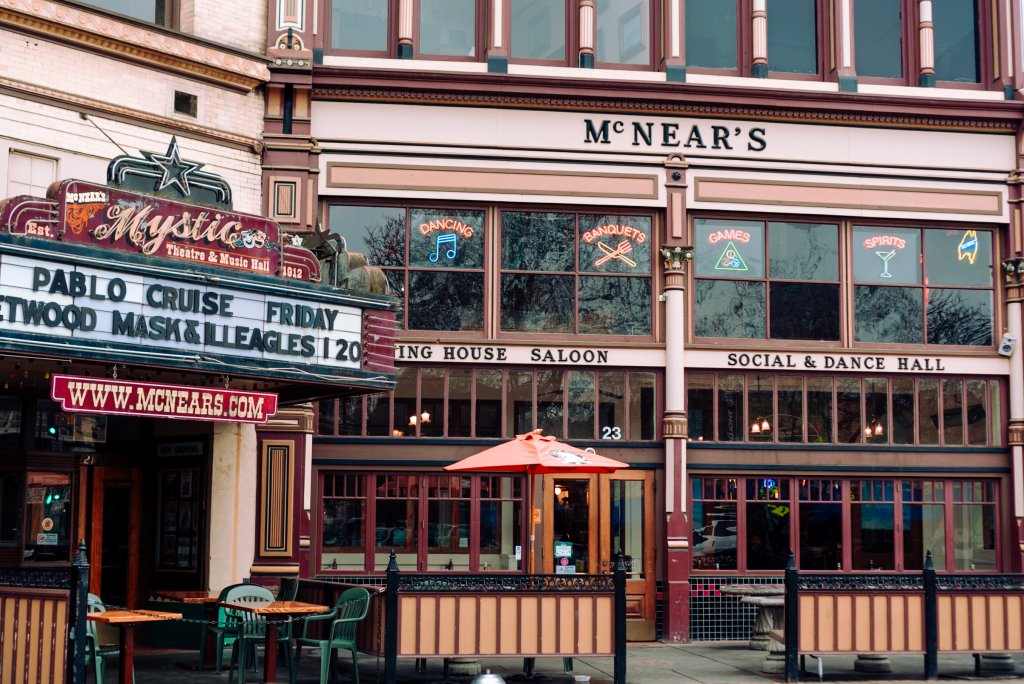 Historic McNear's building and Mystic Theater. Pablo Cruise on Marquee.   Short decorative fence for sidewalk dining area. 